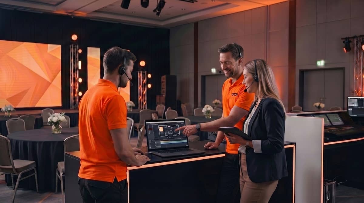 Production team reviewing a corporate event plan with an event planner inside a ballroom before show day.